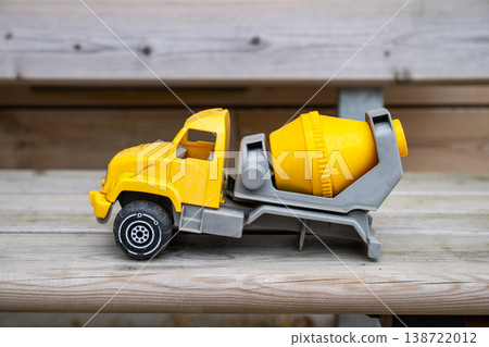 Yellow toy cement mixer truck on wooden bench with blurred rustic background 138722012