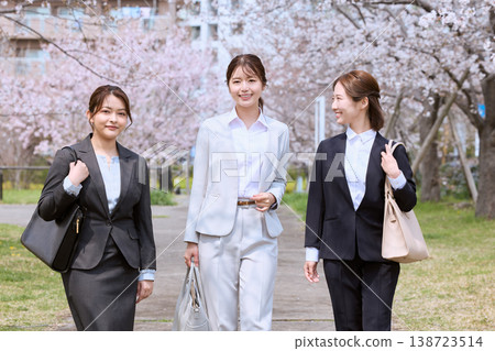 三位身著西裝的年輕女子走在一排櫻花樹下——象徵著春季求職和新進員工。 三位身著西裝的年輕女子走在一排櫻花樹下——象徵著春季求職和新進員工。 138723514