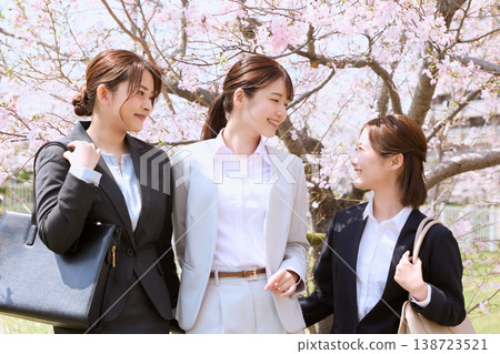 三位身著職業套裝的年輕女子在櫻花樹下微笑交談——這是新員工經歷春季求職季的畫面。 三位身著職業套裝的年輕女子在櫻花樹下微笑交談——這是新員工經歷春季求職季的畫面。 138723521
