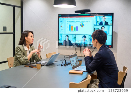 一位來自IT公司的男士和一位女士正在會議室的大顯示器上進行線上會議。 138723969