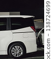 A side view of a white minivan standing in a parking lot at night. 138724699