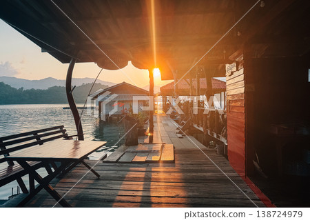 Sun flare through a rustic wooden waterfront homestay at golden hour. Sun flare through a rustic wooden waterfront homestay at golden hour. 138724979