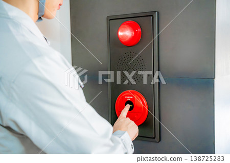 A man in work clothes inspecting an automatic fire alarm system. 138725283