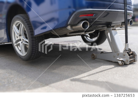 汽車保養工作,包括用千斤頂頂起車輛更換輪胎。 汽車保養工作,包括用千斤頂頂起車輛更換輪胎。 138725653