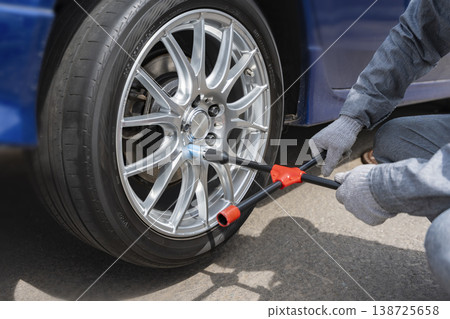 Tire installation process: Tightening wheel nuts with a lug wrench. 138725658