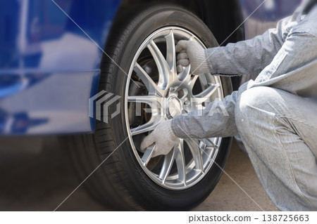 Tire replacement work involves mounting the replacement tire onto the wheel hub. 138725663