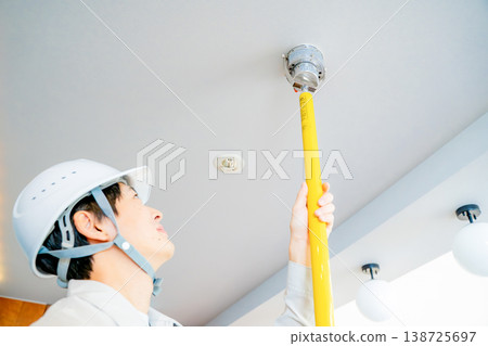 A man in work clothes inspecting an automatic fire alarm system. 138725697