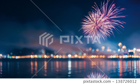 Fireworks light up the night sky above the city skyline. Bright colors burst and reflect off the water, while people gather to watch the display 138726012