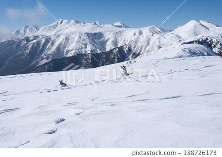 The clear blue sky, the wind patterns etched into the vast snowfield, and the majestic winter mountain range The clear blue sky, the wind patterns etched into the vast snowfield, and the majestic winter mountain range 138726173