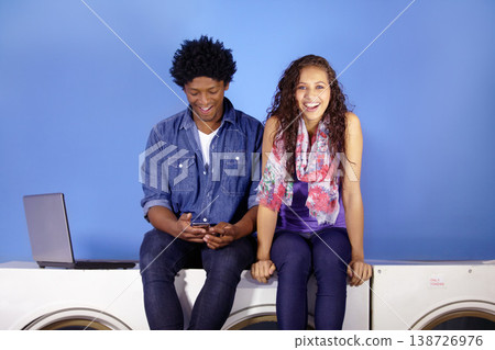 Portrait, happy and couple on a washing machine at a laundromat while in college with social media. Smile, relax and a man and woman with a mobile, laptop and laughing togethre while cleaning clothes Portrait, happy and couple on a washing machine at a laundromat while in college with social media. Smile, relax and a man and woman with a mobile, laptop and laughing togethre while cleaning clothes 138726976