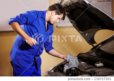 Mechanic, oil and service with a man in a workshop to fix or repair a vehicle during routine maintenance. Engineer, inspection and labor with a young person working in a garage for car assessment Mechanic, oil and service with a man in a workshop to fix or repair a vehicle during routine maintenance. Engineer, inspection and labor with a young person working in a garage for car assessment 138727161