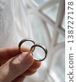 Elegant Close Up of Slender Fingers Holding Silver Mobius Couple Rings by Window Light 138727178