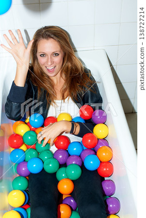 Portrait, throw ball and woman in bathtub for fashion, style and trendy hipster at home. Happy person in tub with color, sphere or plastic with body in bathroom, relax and cool clothes in Canada. 138727214