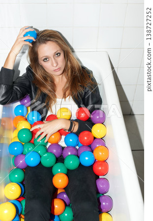 Portrait, balls and woman in bathtub for fashion, style and trendy hipster at home. Serious person in tub with color, sphere or plastic with body in bathroom, relax and edgy or cool clothes in Canada Portrait, balls and woman in bathtub for fashion, style and trendy hipster at home. Serious person in tub with color, sphere or plastic with body in bathroom, relax and edgy or cool clothes in Canada 138727252