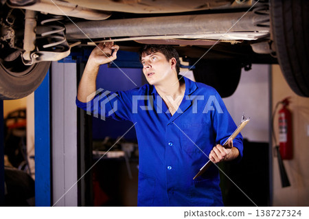 Car, inspection or maintenance with a mechanic man in a garage for a report on a vehicle repair for insurance. Service, professional and expertise with a young engineer in a workshop for assessment 138727324