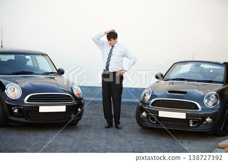 Business man, thinking and choice of car at dealership, shop and store. Confused, customer and decision for motor vehicle sales, doubt to buy convertible and shopping for auto transportation outdoor Business man, thinking and choice of car at dealership, shop and store. Confused, customer and decision for motor vehicle sales, doubt to buy convertible and shopping for auto transportation outdoor 138727392