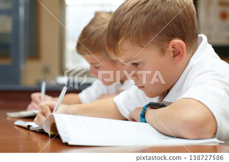 Young students, classroom and writing in books for education, thinking mindset or children on scholarship. Boys, school kids or learning with creative idea on desk, studying and test or work in class Young students, classroom and writing in books for education, thinking mindset or children on scholarship. Boys, school kids or learning with creative idea on desk, studying and test or work in class 138727586