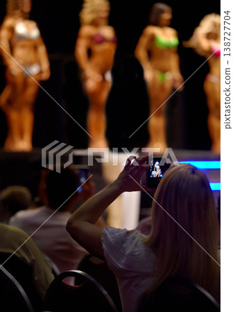 Audience, woman and fitness of bodybuilder or beauty pageant for photography, judge or competition. Female person for photograph, picture or capture of professional models in bikini or lingerie Audience, woman and fitness of bodybuilder or beauty pageant for photography, judge or competition. Female person for photograph, picture or capture of professional models in bikini or lingerie 138727704