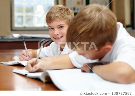 Happy students, classroom and writing in books for education, thinking mindset or children on scholarship. Boys, school kids or learning with creative idea on desk, studying and reading work in class 138727892