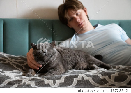 Man relaxing with one eyed cat on bed pet care love and adoption concept 138728842