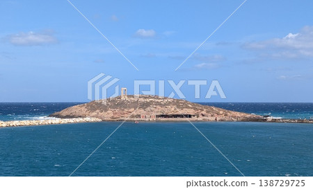 View of a small island with one of the Greek ruins of the Temple of Apollo seen from the ferry 138729725