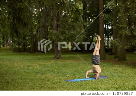 Man performing headstand on grass park with focus and balance Man performing headstand on grass park with focus and balance 138729837