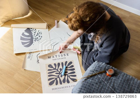 Artist reviews print selection on floor under gentle illumination Artist reviews print selection on floor under gentle illumination 138729863
