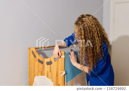 Woman carefully inspects wooden playpen for quality and safety Woman carefully inspects wooden playpen for quality and safety 138729892