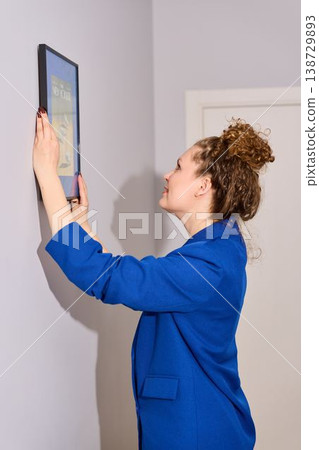 Decor stylist positioning framed artwork on neutral wall accurately Decor stylist positioning framed artwork on neutral wall accurately 138729893