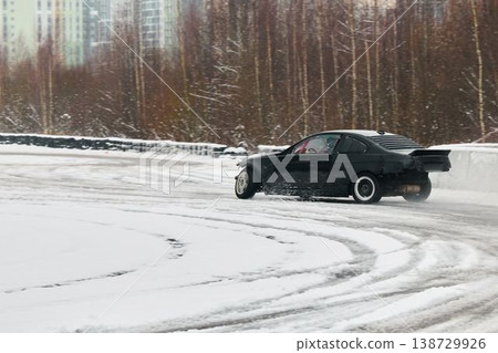 Deftly drifting vehicle on icy circuit with winter scenery Deftly drifting vehicle on icy circuit with winter scenery 138729926