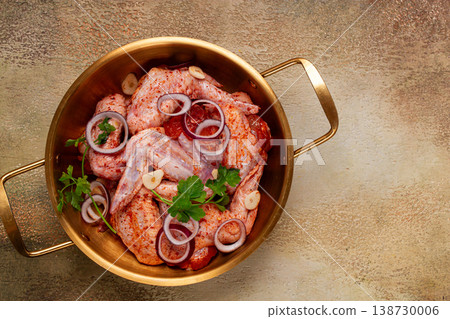 Chicken wings, in a brass saucepan, ready for cooking, grilling or baking, in a home kitchen, no people Chicken wings, in a brass saucepan, ready for cooking, grilling or baking, in a home kitchen, no people 138730006