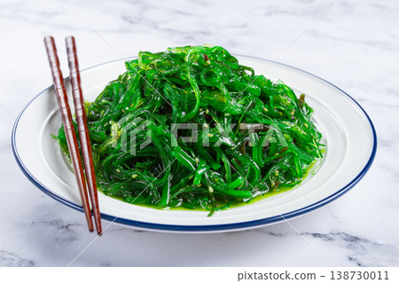 Chuka salad, made from fresh seaweed, with sesame dressing, served on a white plate, with chopsticks, no people, Chuka salad, made from fresh seaweed, with sesame dressing, served on a white plate, with chopsticks, no people, 138730011