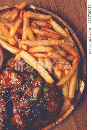 barbecue chicken wings, sprinkled with sesame seeds, with French fries, and sauce, on a wooden plate, rustic style, barbecue chicken wings, sprinkled with sesame seeds, with French fries, and sauce, on a wooden plate, rustic style, 138730012
