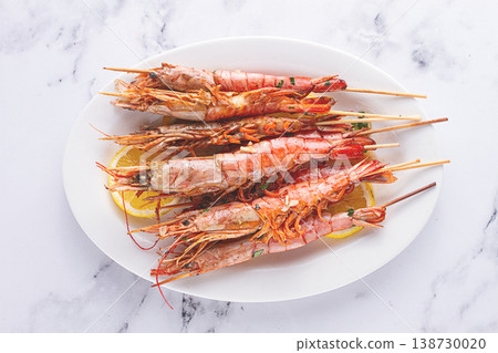 Freshly grilled prawns served, on a white platter ,with lemon slices for a delicious seafood experience 138730020
