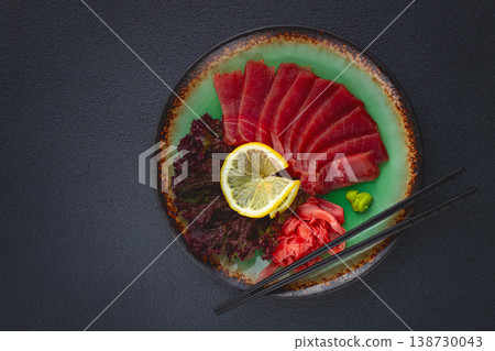 Fresh tuna sashimi served with lemon, wasabi, and pickled ginger on a dark background Fresh tuna sashimi served with lemon, wasabi, and pickled ginger on a dark background 138730043