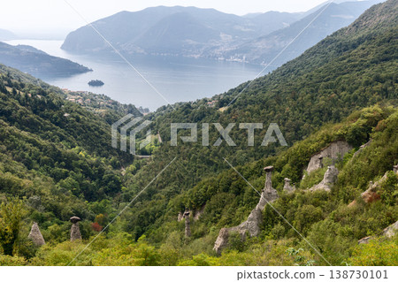 Panoramic view of Pyramids of Zone near Lake Iseo with white hoodoos forested hills calm water Panoramic view of Pyramids of Zone near Lake Iseo with white hoodoos forested hills calm water 138730101