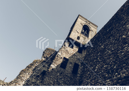 Bell tower and massive castle wall in Cavriana with rugged masonry stark lights film grain mood 138730116