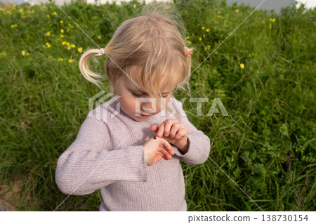 Curious little 4 year old girl examining a ladybug on her hand Curious little 4 year old girl examining a ladybug on her hand 138730154