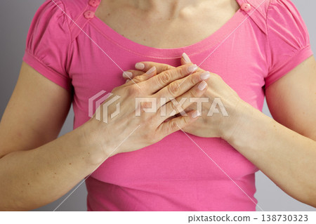 Woman with Hands Clasped Over Heart in Sincere Gesture 138730323
