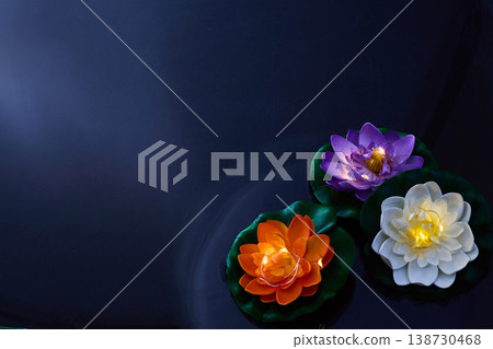 Glowing lotus flowers floating on dark water at night. Vesak day Glowing lotus flowers floating on dark water at night. Vesak day 138730468