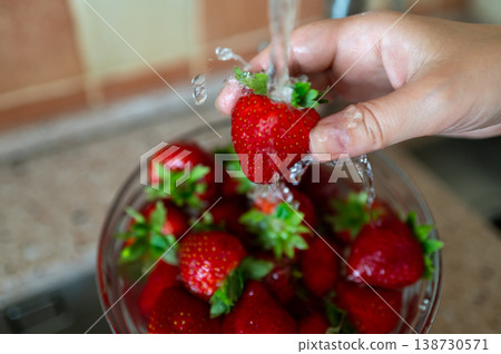 Washing fresh strawberries under running water in kitchen sink, hygiene and healthy eating concept Washing fresh strawberries under running water in kitchen sink, hygiene and healthy eating concept 138730571