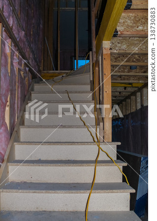 Interior view of unfinished wooden staircase with exposed framing and electrical wiring in a residential construction site 138730883