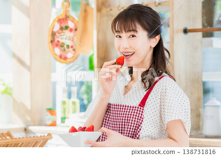 A woman eating strawberries in the kitchen 138731816