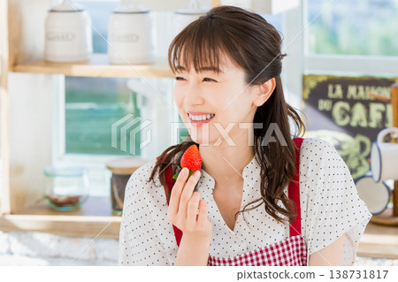 A woman eating strawberries in the kitchen A woman eating strawberries in the kitchen 138731817