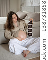 Pregnant woman holding ultrasound scan and touching belly 138731858