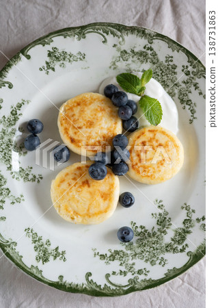 Cheesecakes with blueberries and sour cream lying on vintage plate Cheesecakes with blueberries and sour cream lying on vintage plate 138731863