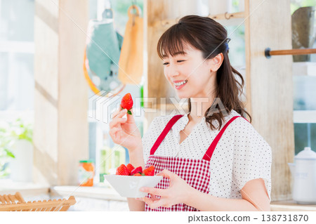 A woman picking and eating strawberries in the kitchen A woman picking and eating strawberries in the kitchen 138731870