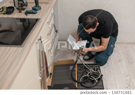 A plumber is replacing a faucet in the kitchen. A plumber is replacing a faucet in the kitchen. 138731881