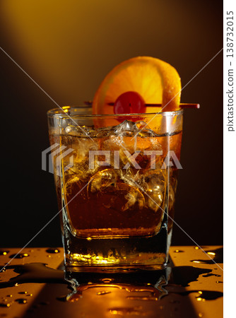 Old fashioned cocktail in a sweating glass on a wet black table. Old fashioned cocktail in a sweating glass on a wet black table. 138732015