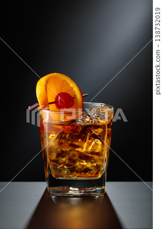Old fashioned cocktail in a sweating glass on a black table. Old fashioned cocktail in a sweating glass on a black table. 138732019